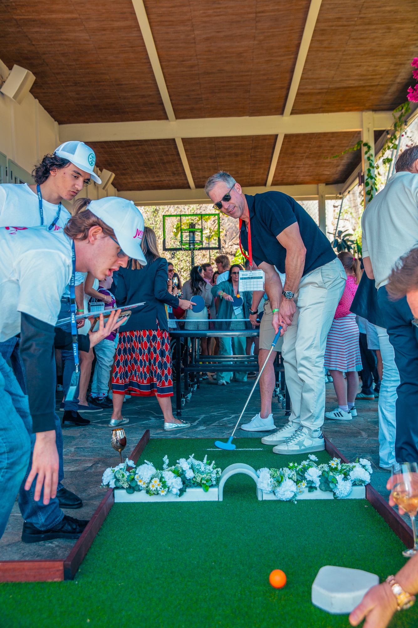 Guests watching mobile mini-golf under a covered pavilion at an indoor venue
